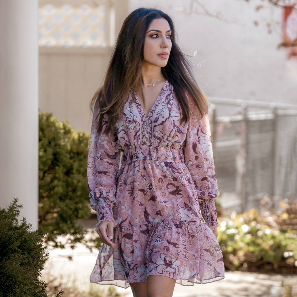 Woman wearing a floral pink dress, enjoying a sunny day outdoors.