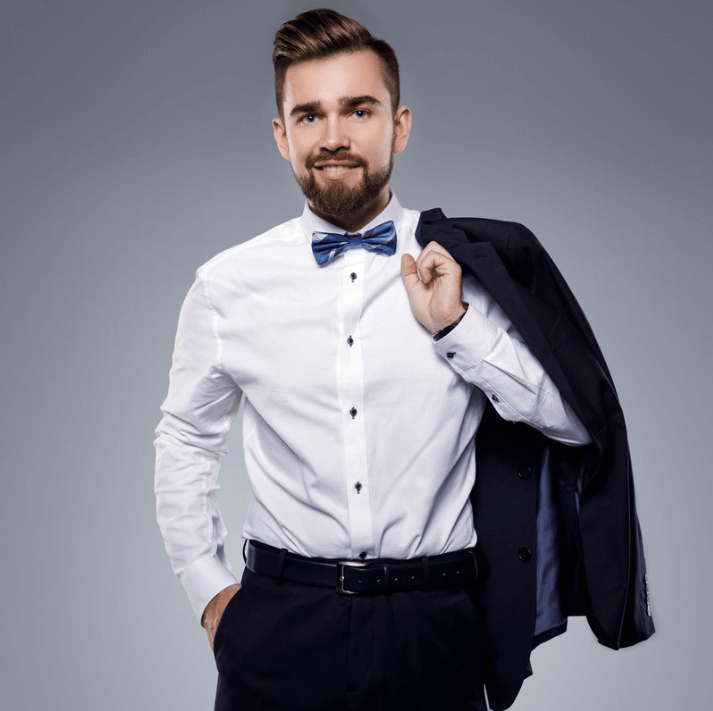 Stylish man in white shirt and bow tie holding a jacket, showcasing modern gentleman fashion.