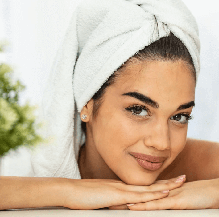 A young woman with a towel on her head relaxing and showing smooth skin after using Herbal Reliefing Cream.