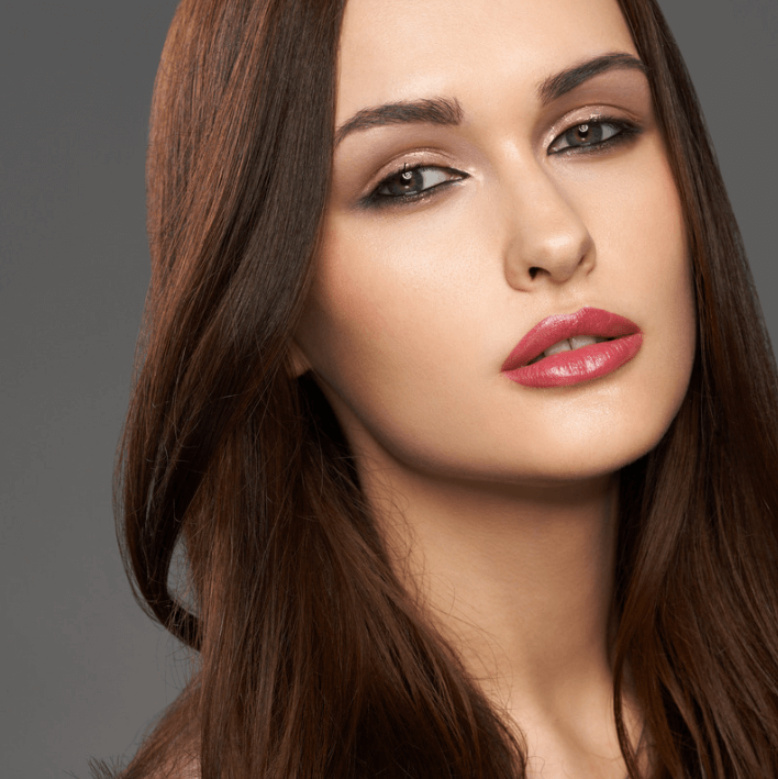 Ultra Body Oil on smooth, radiant skin showcased by a model with long brown hair and bold lips.