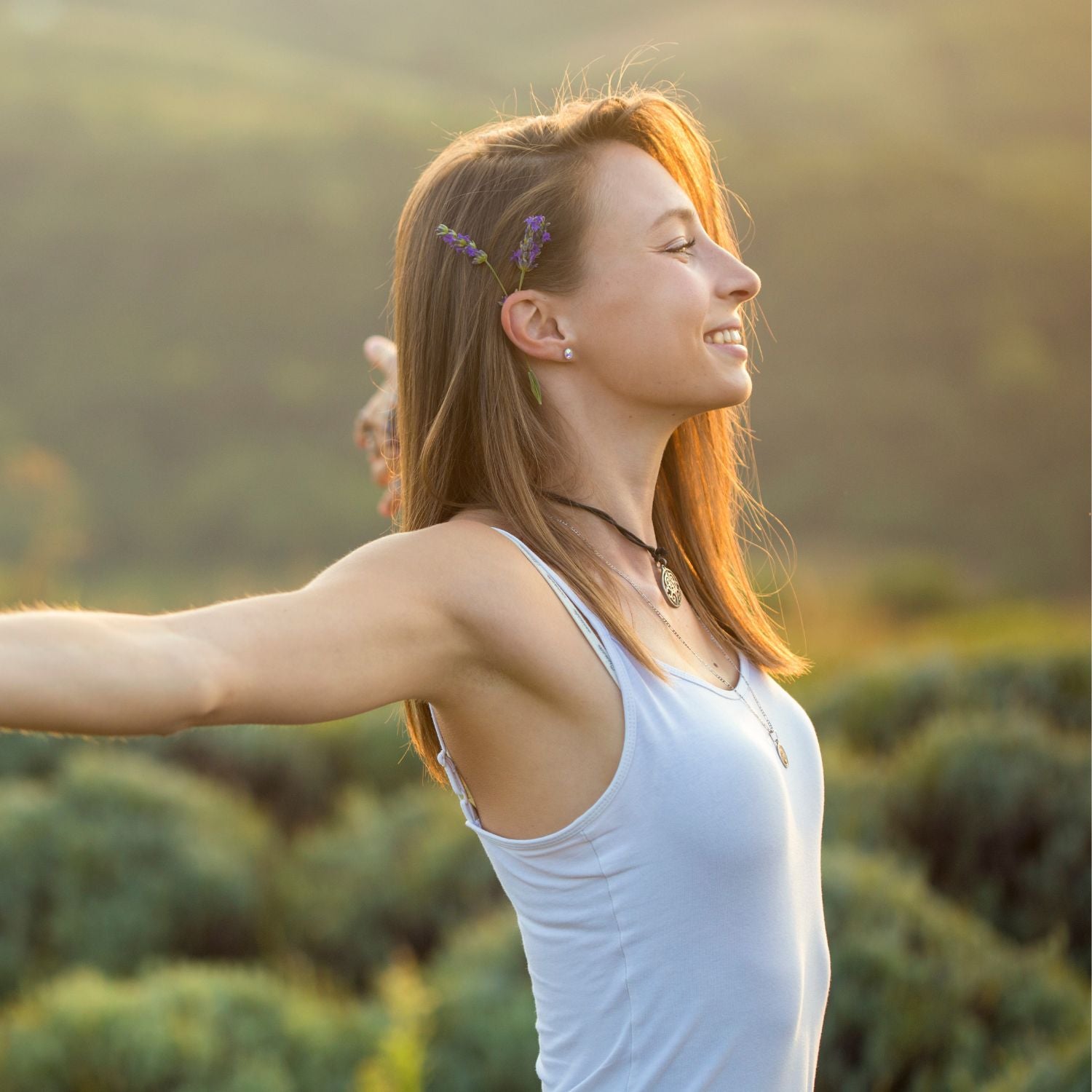 Woman enjoying nature with arms outstretched, symbolizing freedom and well-being.