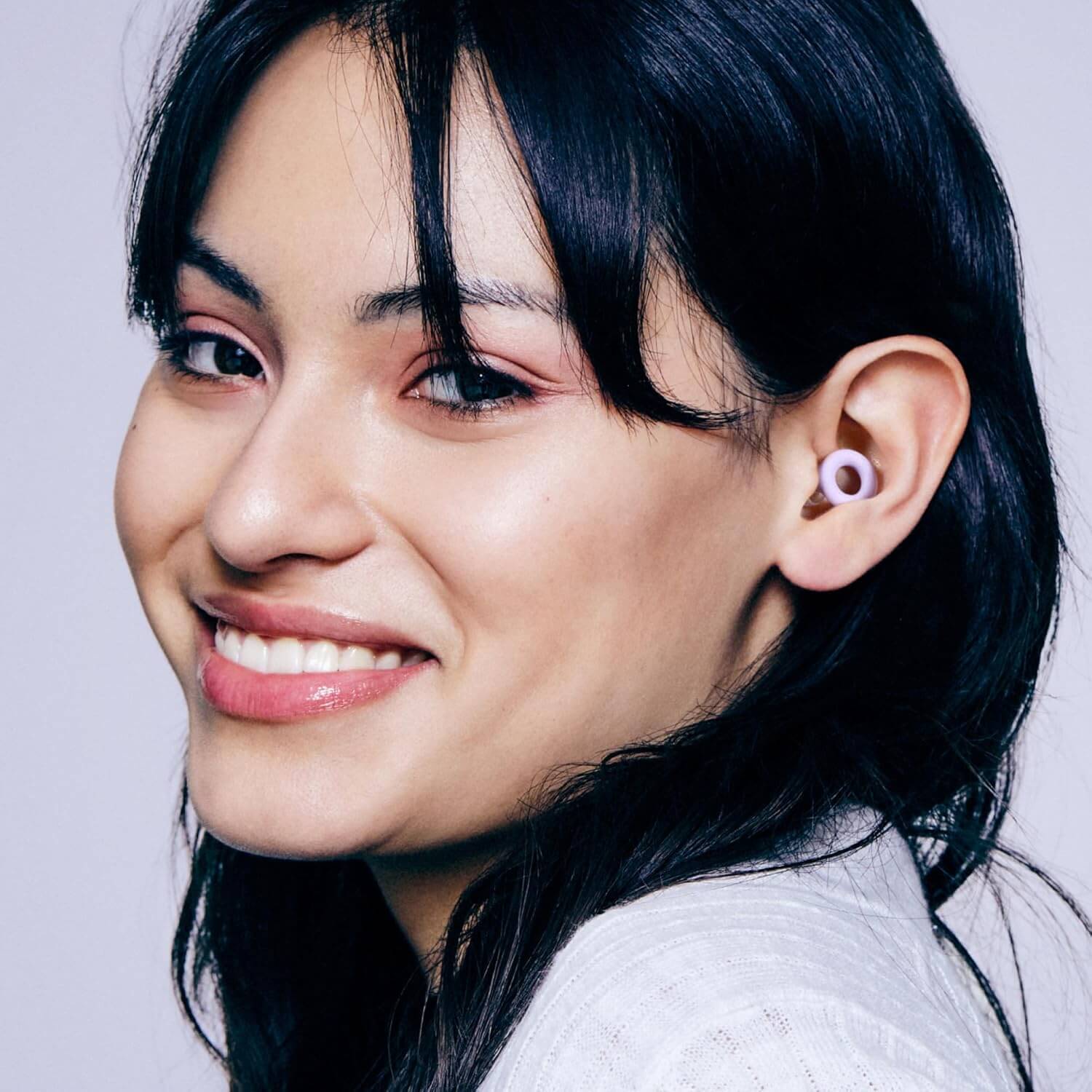 Zentheca Quiet Earplugs worn by a smiling woman, showcasing their ultra-comfortable fit and noise reduction features.